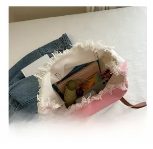 Vue de dessus d'un grand sac cabas en toile contenant des livres, parapluie et mobile