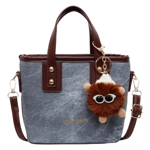 Blue denim bucket bag with brown leather trim and a cute furry monster charm