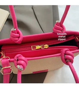 Gros plan du curseur en métal doré lisse sur le sac cabas tissé beige et rose