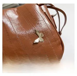 Detail of brown embossed leather cloud bag featuring a vintage silver butterfly metal buckle