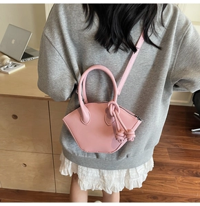 Minimalist pink fan-shaped handbag worn by a model in a stylish office setting