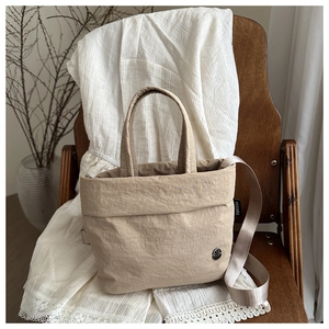 Borsa tote minimalista in nylon beige con tracolla mostrata in un ambiente lifestyle