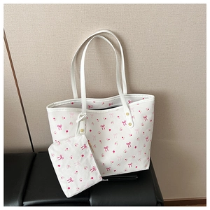 Detail of white leather tote set featuring pink floral and bow patterns with twin handles
