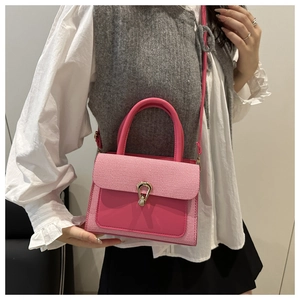 Detailed view of a pink crossbody bag with striped texture and golden lock on a model