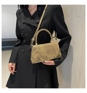 Detail of vintage gold textured crossbody bag held by a model in a black dress