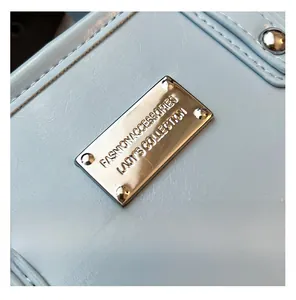 Close-up of light blue bucket bag with silver metal plaque and precise stitching