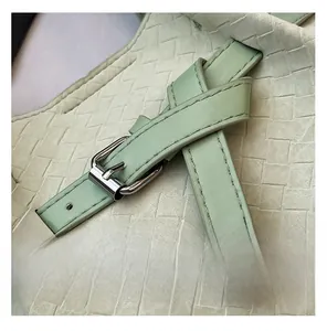 Detail of mint green woven tote bag showing leather texture and silver buckle