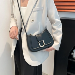 Minimalist black saddle bag with golden U-shaped buckle on model with white blazer
