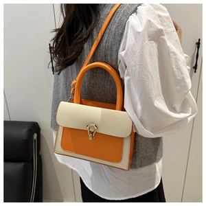 Detail view of woven leather patchwork crossbody bag with gold-tone horseshoe buckle