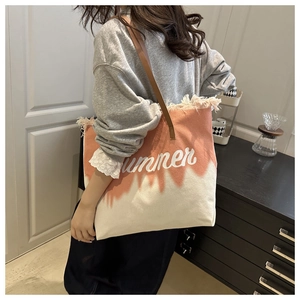 Détail du sac cabas en toile avec dégradé orange, franges et bandoulières en cuir