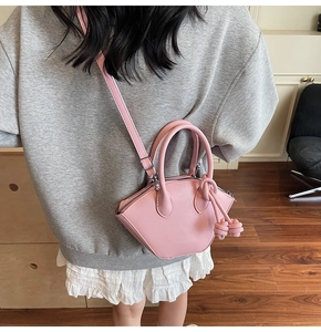 Detail view of a stylish pink mini bucket handbag with knot accents on a model