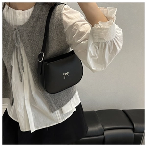 Detail of black semi-circle leather bag with silver bow buckle and adjustable strap