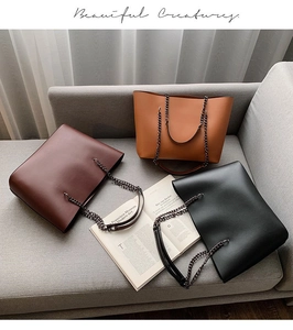 Three large tote bags in brown, tan, and black with leather-chain straps on a sofa