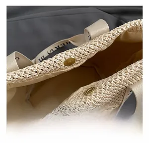 Detail of golden magnetic closure and woven texture on beige straw tote handbag