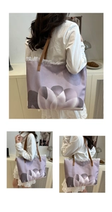 Detail of lavender canvas tote with floral print, fringe edges and brown leather straps