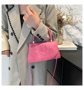 Detailed shot of pink crossbody bag with matte texture and metallic buckle handle strap