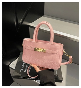 Detail of pink croc-embossed leather tote with gold hardware lock on design books