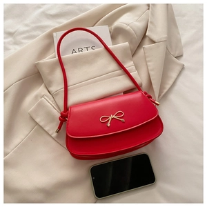 Detail of red leather shoulder bag with gold bow clasp and phone for size comparison