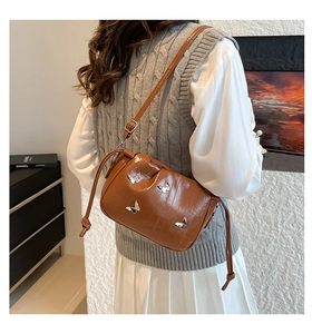 Detail of pleated brown PU leather crossbody bucket bag with silver butterfly charms
