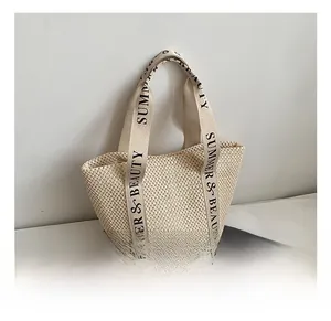 Detail of handwoven beige straw tote bag with black SUMMER & BEAUTY lettered straps