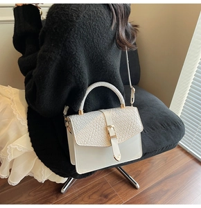 Détail du sac bandoulière blanc avec rabat à texture tissée et finitions dorées