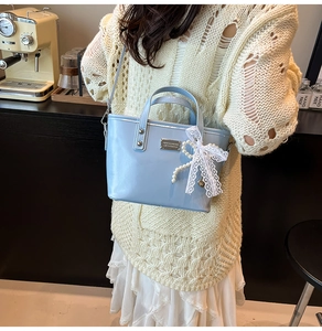 Side view of light blue bucket bag with pearl chain and lace bow in a cafe setting