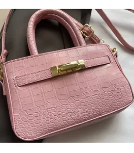 Detail of pink croc-embossed synthetic leather bag with golden metallic lock buckle