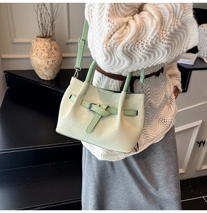 Detail of mint green pleated bucket bag with woven leather texture and crossbody strap