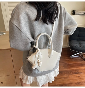 Detailed view of white glossy fan-shaped handbag with knot handle detail