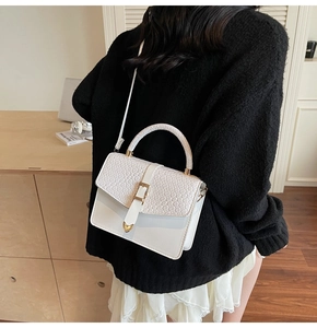 Détail du sac blanc à motif crocodile avec boucle dorée et bandoulière sur le côté