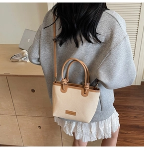 Détail du sac seau tissé avec bordure en cuir marron et bandoulière réglable amovible