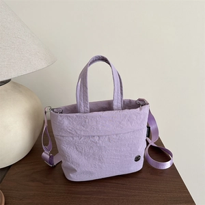 Borsa a tracolla minimalista in tela stropicciata viola chiaro da donna su tavolo