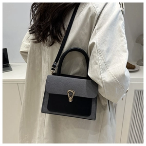 Detail of color-block crossbody bag with gold pear-shaped clasp worn by model in trench coat