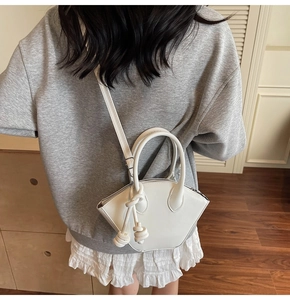 Vista posteriore di una modella con borsa a tracolla bianca a trapezio con nodi