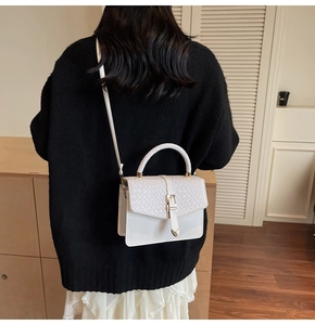 Détail du sac bandoulière en cuir blanc avec rabat à texture animale et boucles dorées