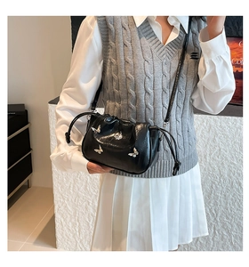 Close-up of black ruched cloud bag featuring silver butterfly charms and drawstring closure