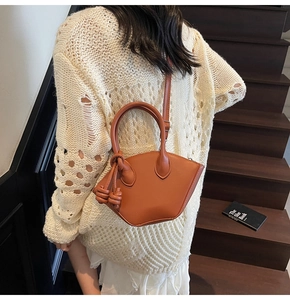 Vue détaillée d'un sac seau marron vintage pour femme porté avec un pull en maille blanc