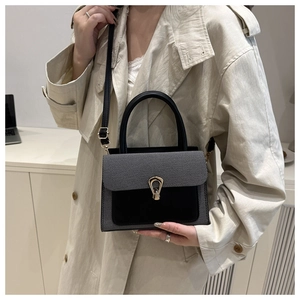 Detail of stylish textured leather crossbody bag featuring gold horseshoe twist lock closure