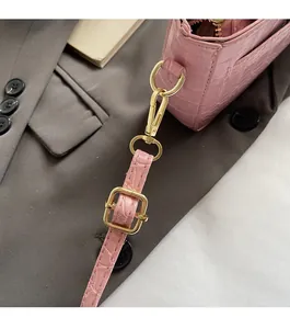 Macro detail of golden metal buckle and pink crocodile pattern leather on handbag