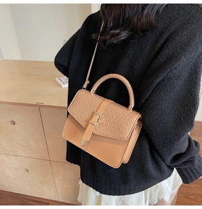 Détail du sac camel avec rabat tissé, boucle cœur dorée et finitions en cuir lisse