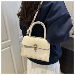 Detail of a chic cream crossbody bag featuring woven texture and a gold horseshoe lock