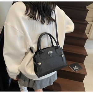 Detail der schwarzen Handtasche mit Lychee-Maserung, Silberverschluss und Schultergurt
