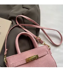 Detailed view of pink croc-embossed leather handbag with adjustable shoulder strap