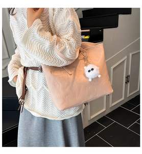 Detail of pink faux leather tote bag with floral embossing and plush monster charm