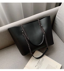Detail of black leather tote bag featuring white contrast stitching and chain strap