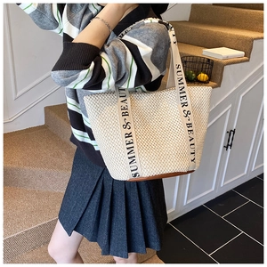Detail of straw tote bag with brown leather bottom and Summer & Beauty strap design
