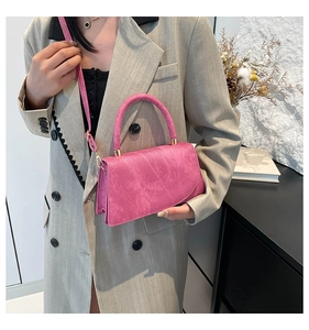 Detail of fuchsia suede-textured small square bag with top handle and slim strap