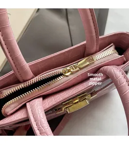 Detailed macro view of smooth gold zipper and crocodile embossed texture on pink handbag