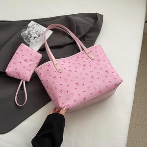 Pink floral tote bag with bow pattern and matching small pouch on a stylish grey blazer