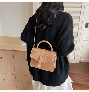 Détail d'un sac bandoulière beige avec rabat tissé et boucle métallique décorative